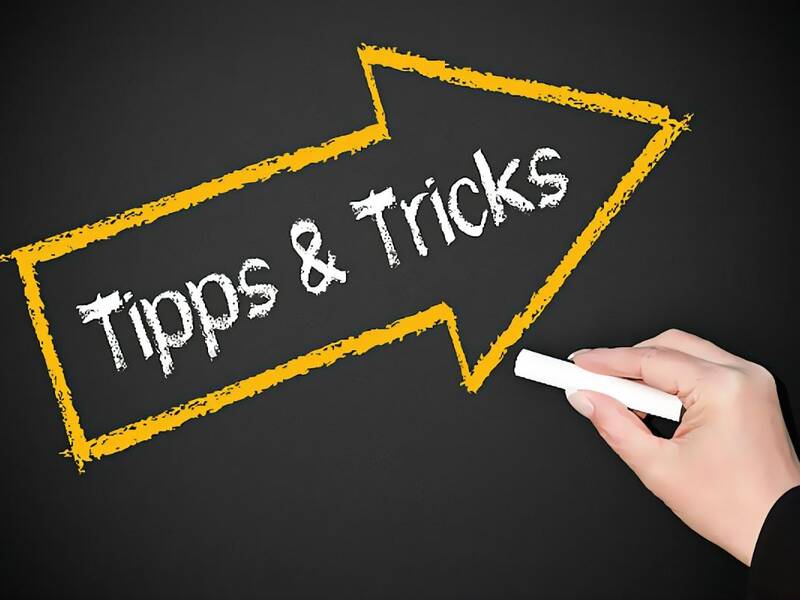 Hand schreibt Tipps $ Tricks mit Kreide an eine Tafel